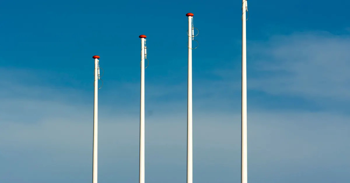 Mâts porte-drapeaux encore vides devant un commerce, avant installation des visuels
